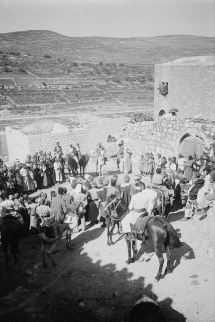Crowd gathered on village hill (all looking at man on house. Turkish flag)