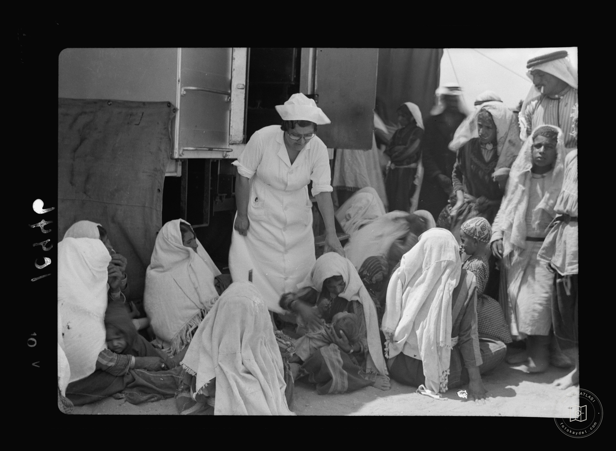 One of the nurses among peasant women & children beside the van — mobile eye clinic near Gaza