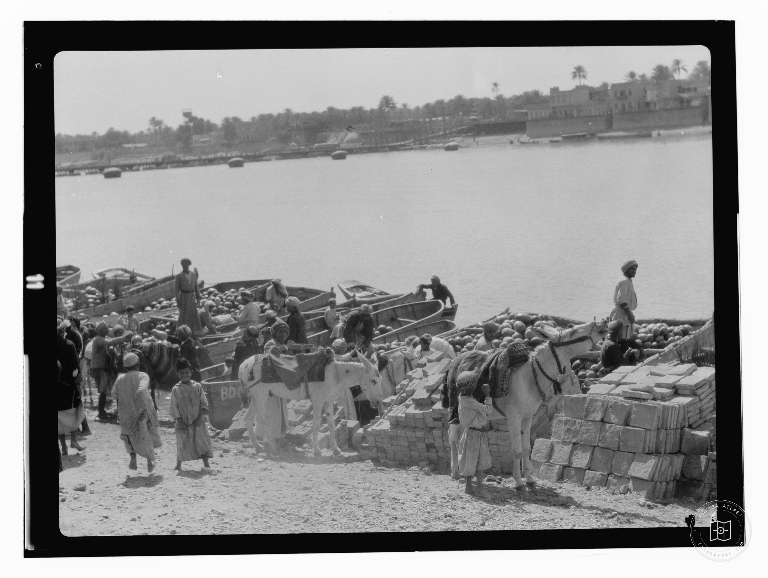 boats being unloaded at river with city in background